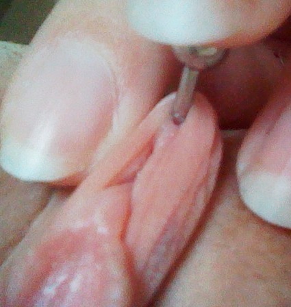 Shallow vertical clit hood piercing from underside view
